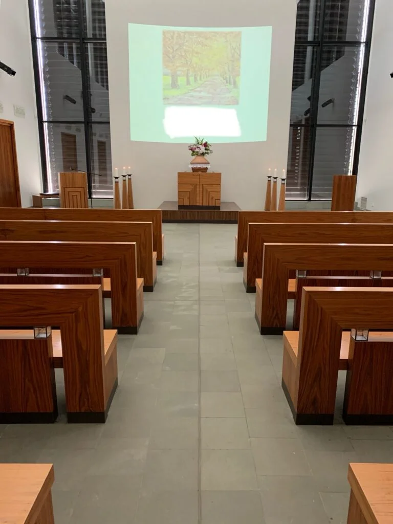 Modern smuteční síň s dřevěnými lavicemi a projekcí